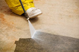 worker performing sidewalk pressure washing