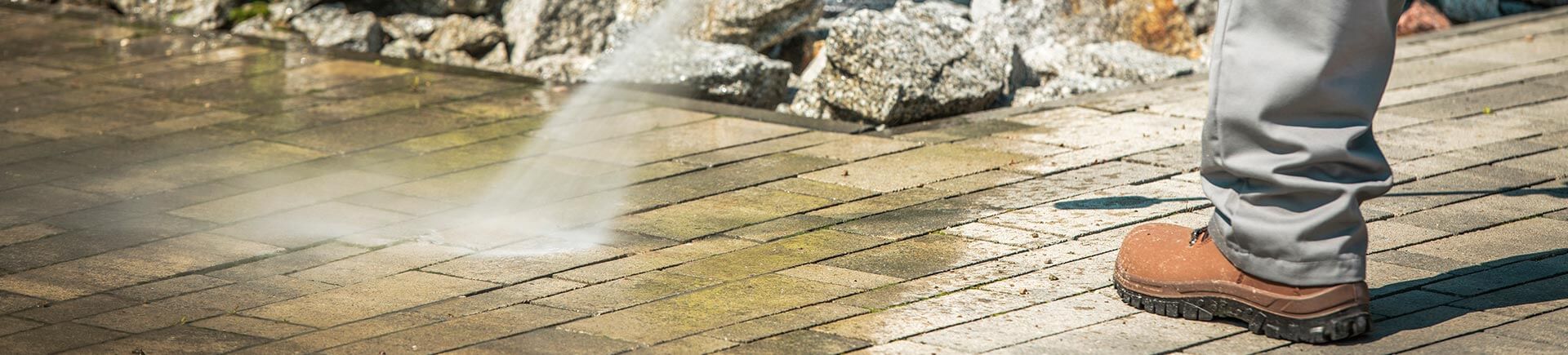 Cobble Brick Driveway Pressure Washing by Worker